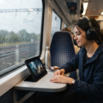 Commuter on a train watching a show on a budget tablet with headphones on