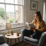 Woman reading in a compact armchair by the window of a small UK flat